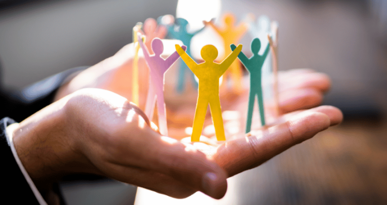 Circle of paper figures standing on businessperson's outstretched palms, representing middle leadership in schools