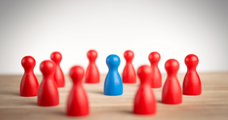 Group of red game pieces, surrounding a blue game piece, representing collective punishment