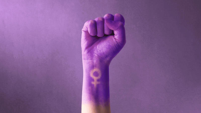 Fist painted purple, with feminine symbol, representing International Women's Day