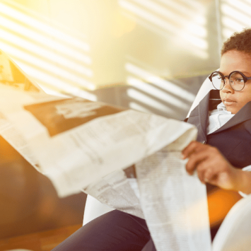 Young kid reading large newspaper