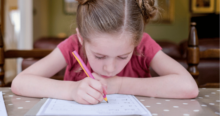 Girl practising handwriting, representing the idea of teaching handwriting in school