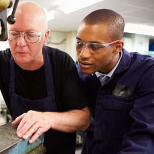 Apprentice looking over shoulder of engineer, representing National Apprenticeship Week