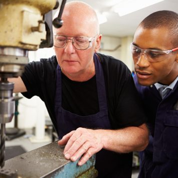 Apprentice looking over shoulder of engineer, representing National Apprenticeship Week