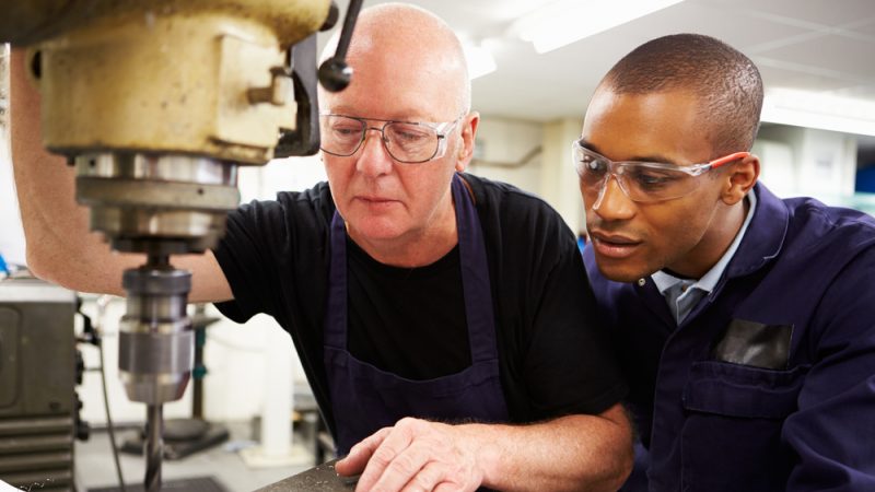 Apprentice looking over shoulder of engineer, representing National Apprenticeship Week