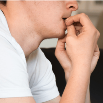 Anxious boy in school uniform biting nails, representing EBSA