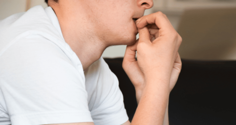 Anxious boy in school uniform biting nails, representing EBSA