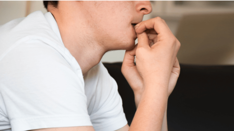 Anxious boy in school uniform biting nails, representing EBSA