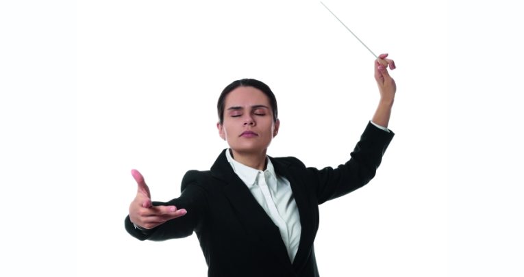 photo of an orchestra conductor with eyes closed and baton raised