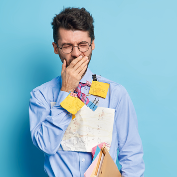 Photo of a fatigued-looking besuited male teacher yawning, with an assortment of Post-it notes stuck to his torso