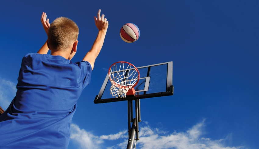 Photo of teenage boy throwing basketball into basketball hoop