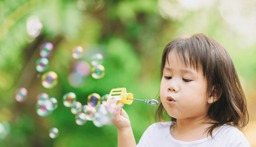 Girl blowing bubbles outside