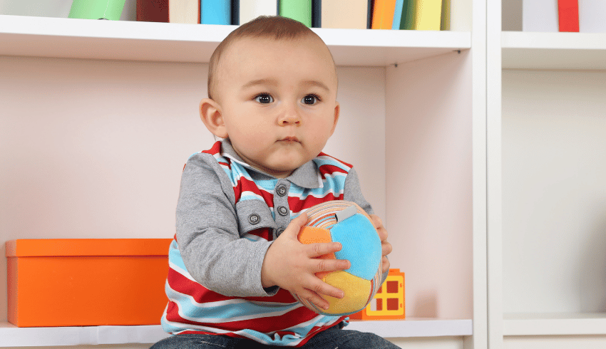 Toddler about to roll a ball