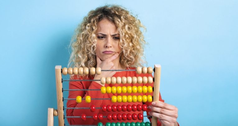 Photo of confused woman holding an abacus, representing maths teachers