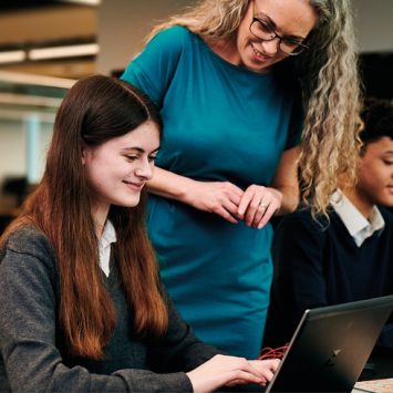 Photo of two students with laptops and a teacher in the classroom, representing Online Education Accreditation Scheme