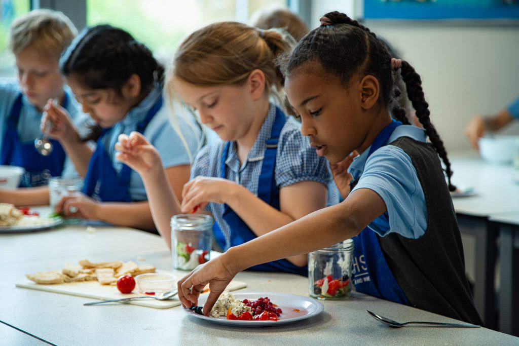 Primary school children in Leiths Academy aprons making a recipe in the classroom