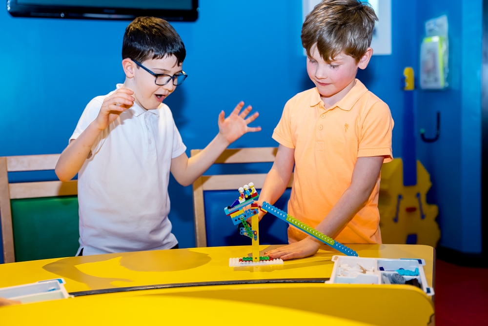 Two primary school boys building a LEGO model in a workshop at a LEGOLAND Discovery Centre