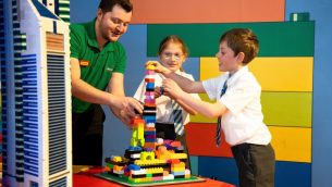 Two Key Stage 2 pupils building with LEGO, supported by an adult workshop leader