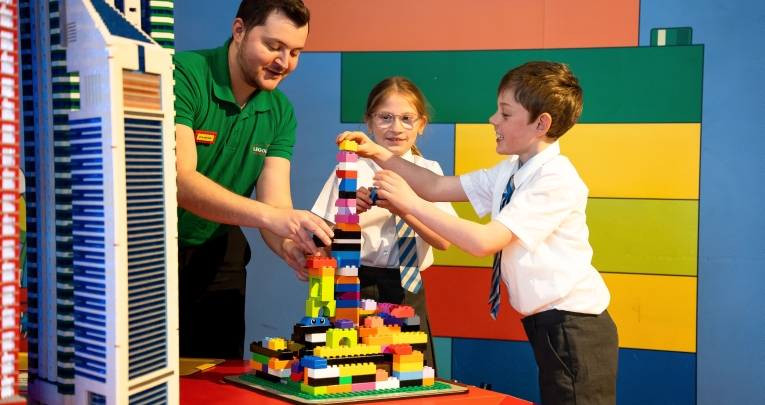 Two Key Stage 2 pupils building with LEGO, supported by an adult workshop leader