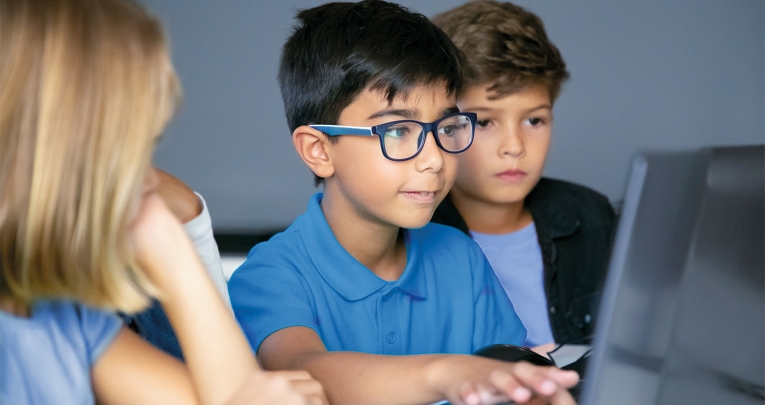 A schoolboy using a laptop in a classroom