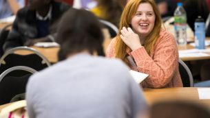 A primary school teacher sitting at a table smiling