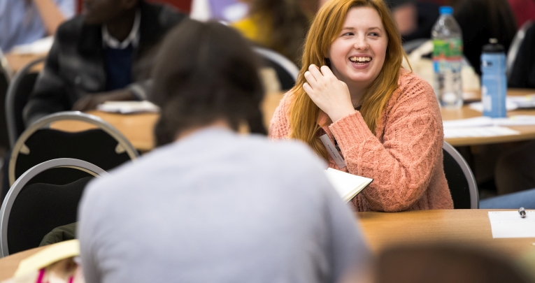 A primary school teacher sitting at a table smiling