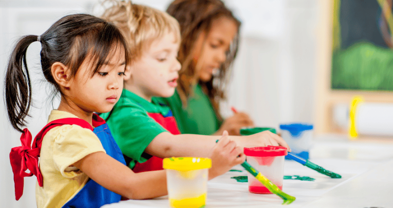 Three young children painting, representing art assessment