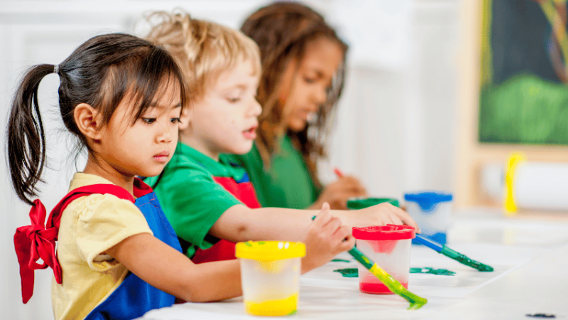 Three young children painting, representing art assessment