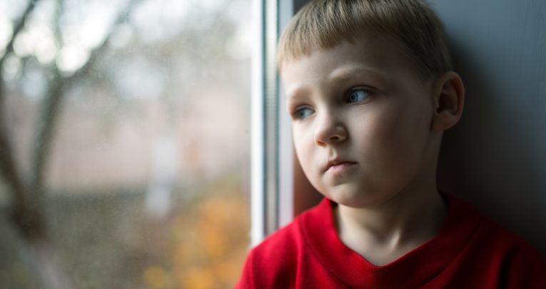 Photo of young boy looking out of the window