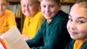 A school girl reading book alongside three school boys