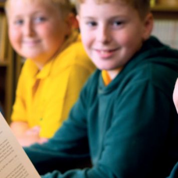 A school girl reading book alongside three school boys