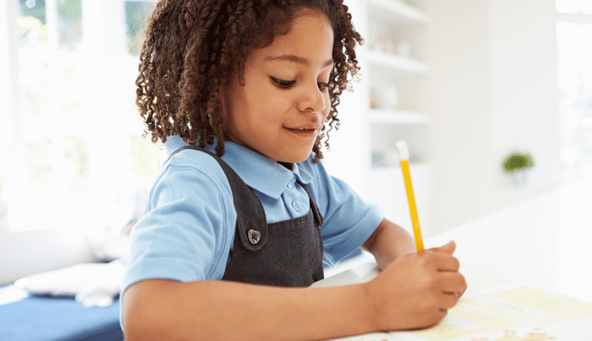 Child in school uniform writing, representing the idea of teaching handwriting