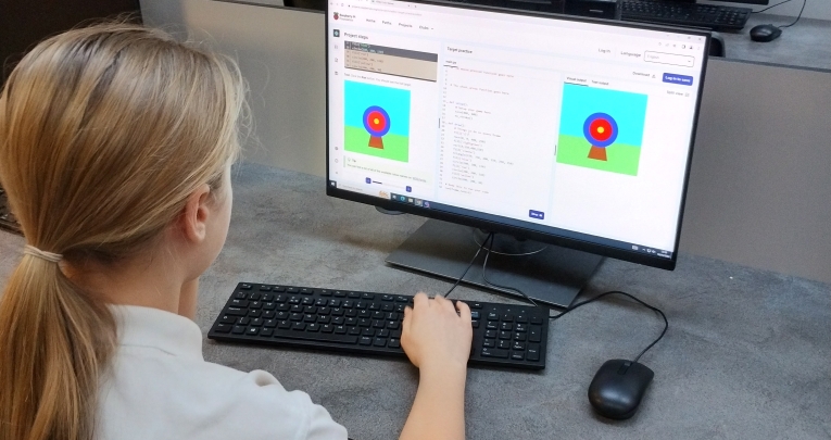 A school girl writing computer code on a computer