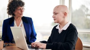 A secondary school girl working at a laptop with a tutor