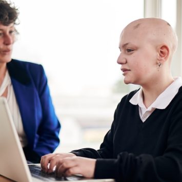 A secondary school girl working at a laptop with a tutor