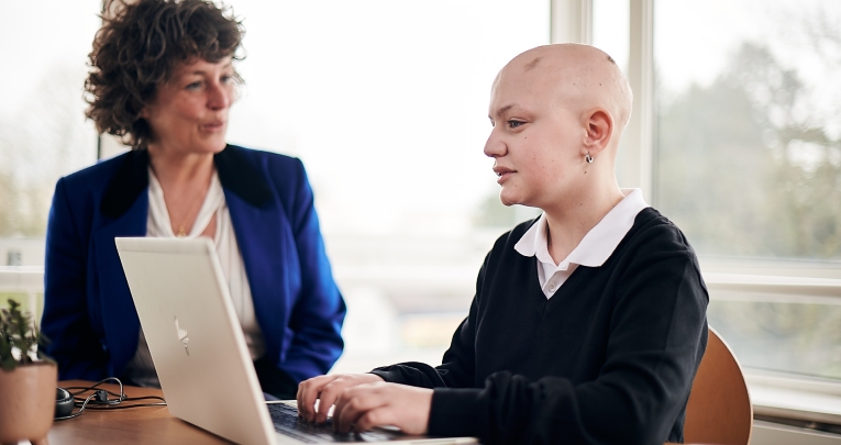 A secondary school girl working at a laptop with a tutor