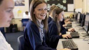 A primary schoolgirl sitting at a desk with a computer