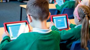 Primary school students sitting and working on tablets