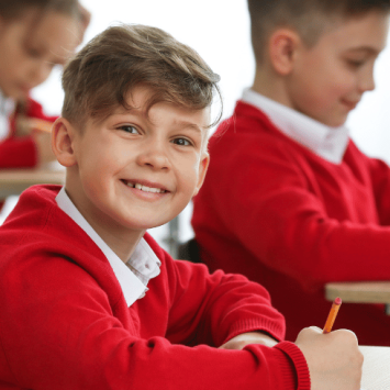 Smiling boy in school uniform doing SATs reading paper