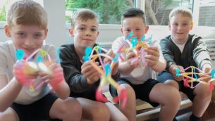 Four schoolboys holding Strawbees resources