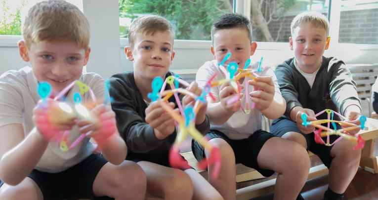 Four schoolboys holding Strawbees resources