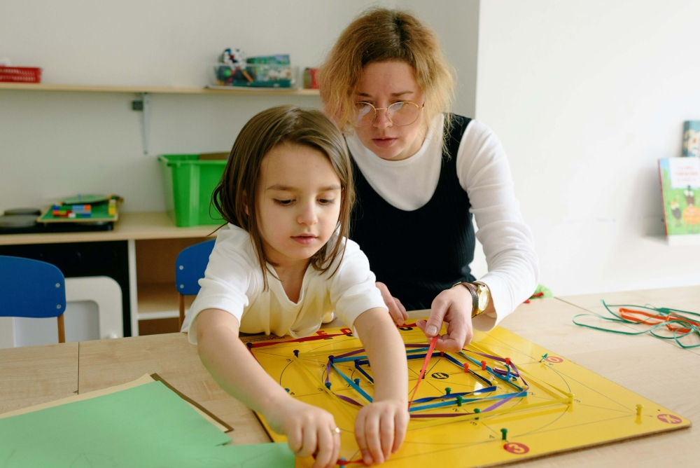 A teacher supporting a young girl in a learning activity