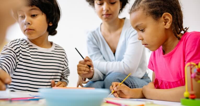 Two children sitting at a table and painting