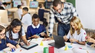 A group of primary school children at a desk using ASUS laptops