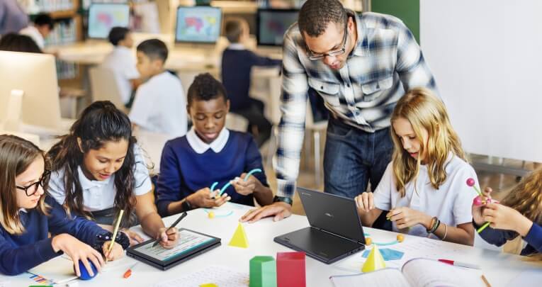 A group of primary school children at a desk using ASUS laptops