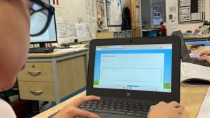 A primary school boy using Tapestry on a laptop in a classroom