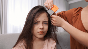 Parent combing girl's hair with nit comb, representing head lice in schools