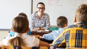 A school teacher smiling at a class of children