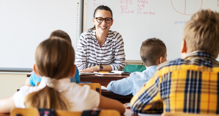 A school teacher smiling at a class of children