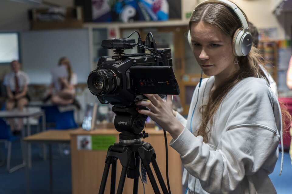 A secondary school girl filming with a video camera